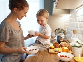 Alimentos energéticos clave para niños Madre y niño en la cocina, sentado en la mesada con un tazón, queso y pan, alimento energético